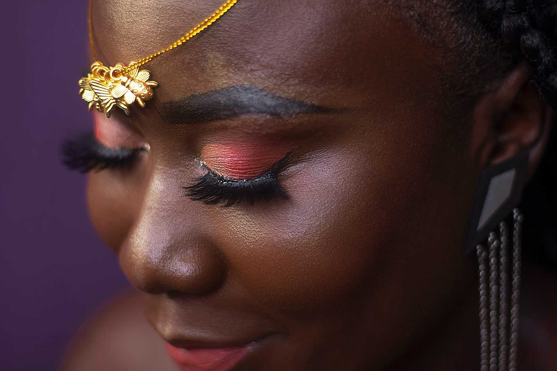 Close-up of a woman's face with floral headpiece and vibrant makeup.